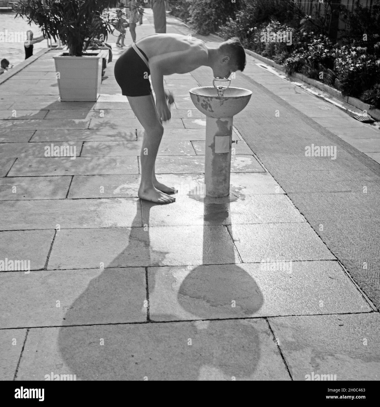 Junge am Trinkwasserspender im Opelbad am Südhang des Nerobergs im Norden von Wiesbaden, Deutschland 1930er Jahre. Boy at a water dispenser at the Opelbad swimming pool in the North of Wiesbaden, Germany 1930s. Stock Photo