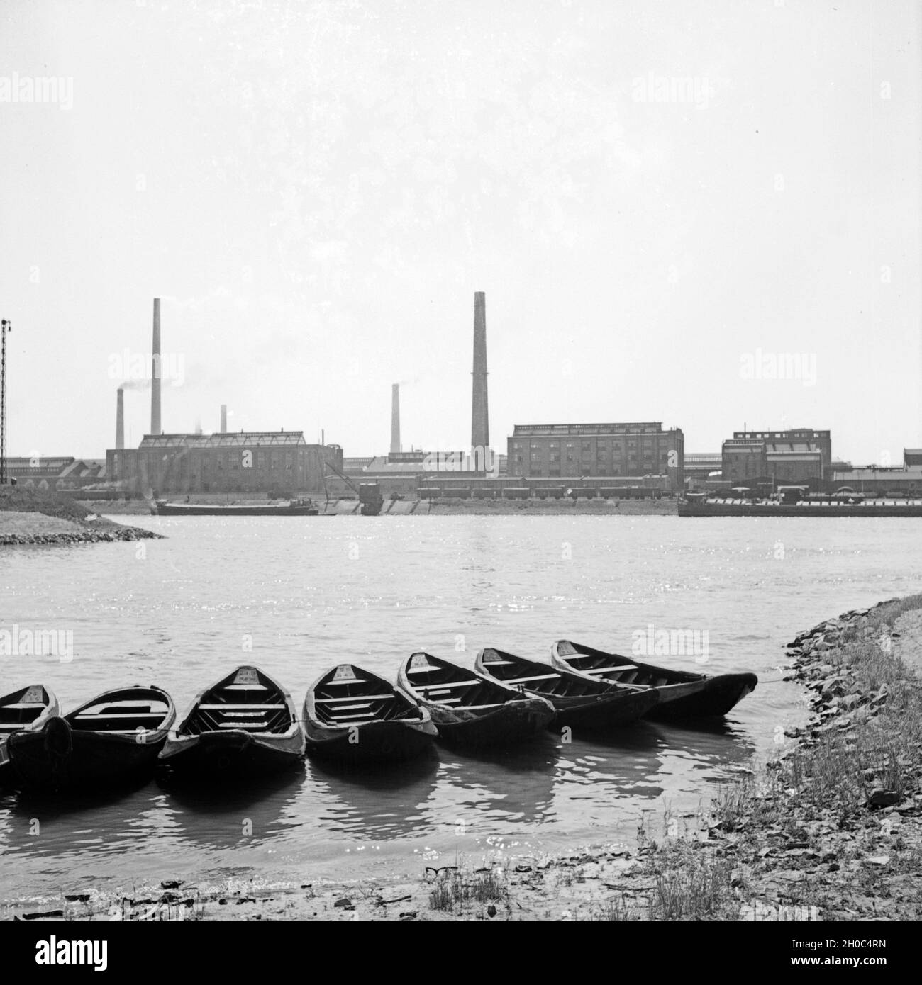 Sieben Ruderboote am Rheinufer in Ludwigshafen, gegenüber den BASF Werken, Deutschland 1930er Jahre. Seven rowing boats at the shore of river Rhine, opposite from the BASF works, Germany 1930s. Stock Photo