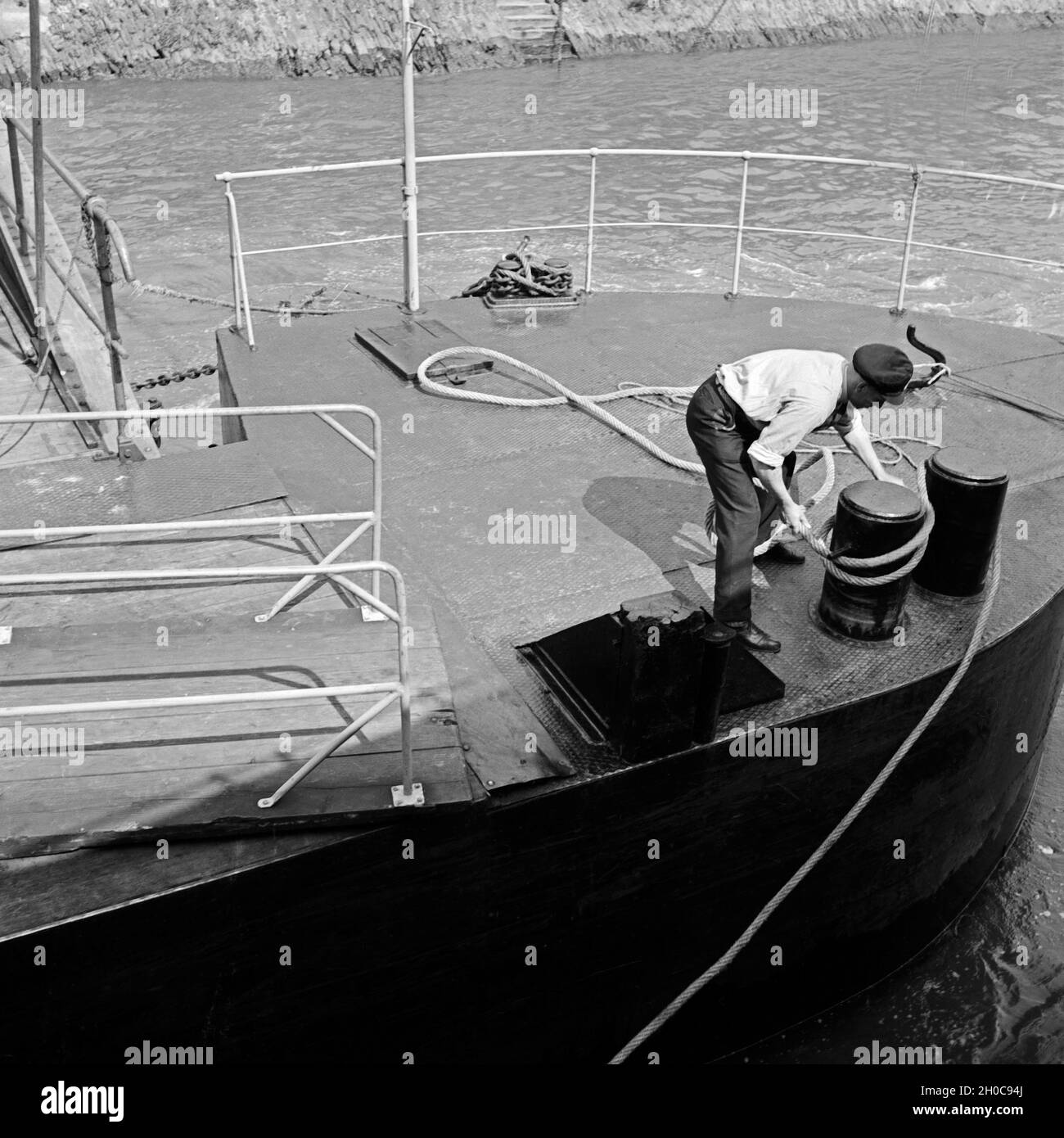 Flußschiffer beim Festmachen des Schiffes am Ausleger, Deutschland 1930er Jahre. Boatman fixing the ship at the ponton, Germany 1930s. Stock Photo