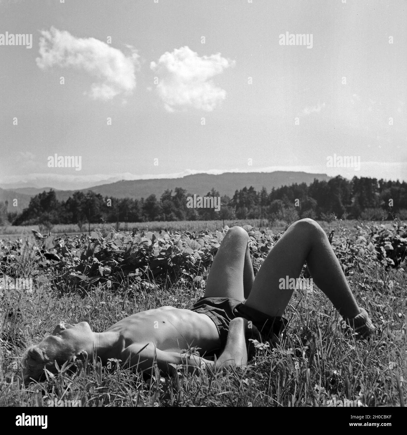 Erschöpfter Hitlerjunge liegt in einer Wiese, Österreich 1930er Jahre. Exhausted Hitler youth boy lying on a lawn, taking a nap, Austria 1930s. Stock Photo