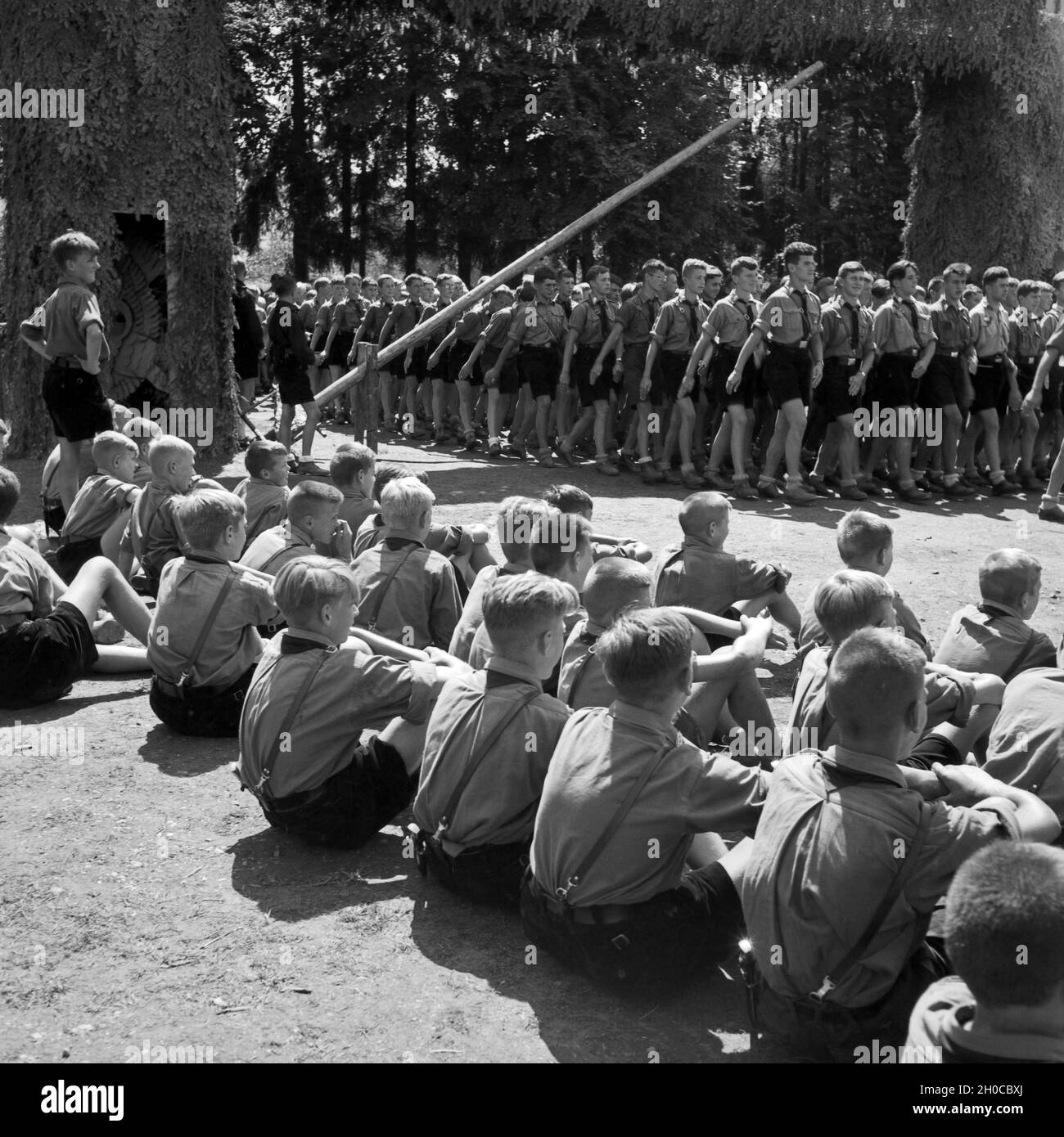 Stolz schauen sich Pimpfe des Jungvolks den Einmarsch der größeren Hitlerjungen ins Hitlerjugend Lager an, Österreich 1930er Jahre. Proudly the recruits, called 'Pimpfe', watch the elder Hitler youths marching in to the Hitler youth camp, Austria 1930s. Stock Photo