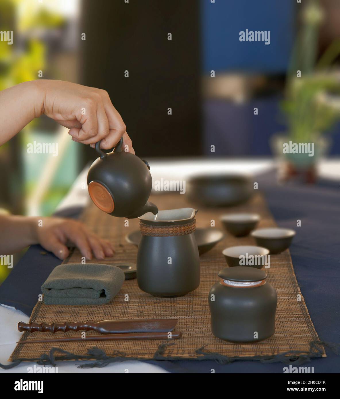 A womans hands pour water from a teapot during a tea ceremony