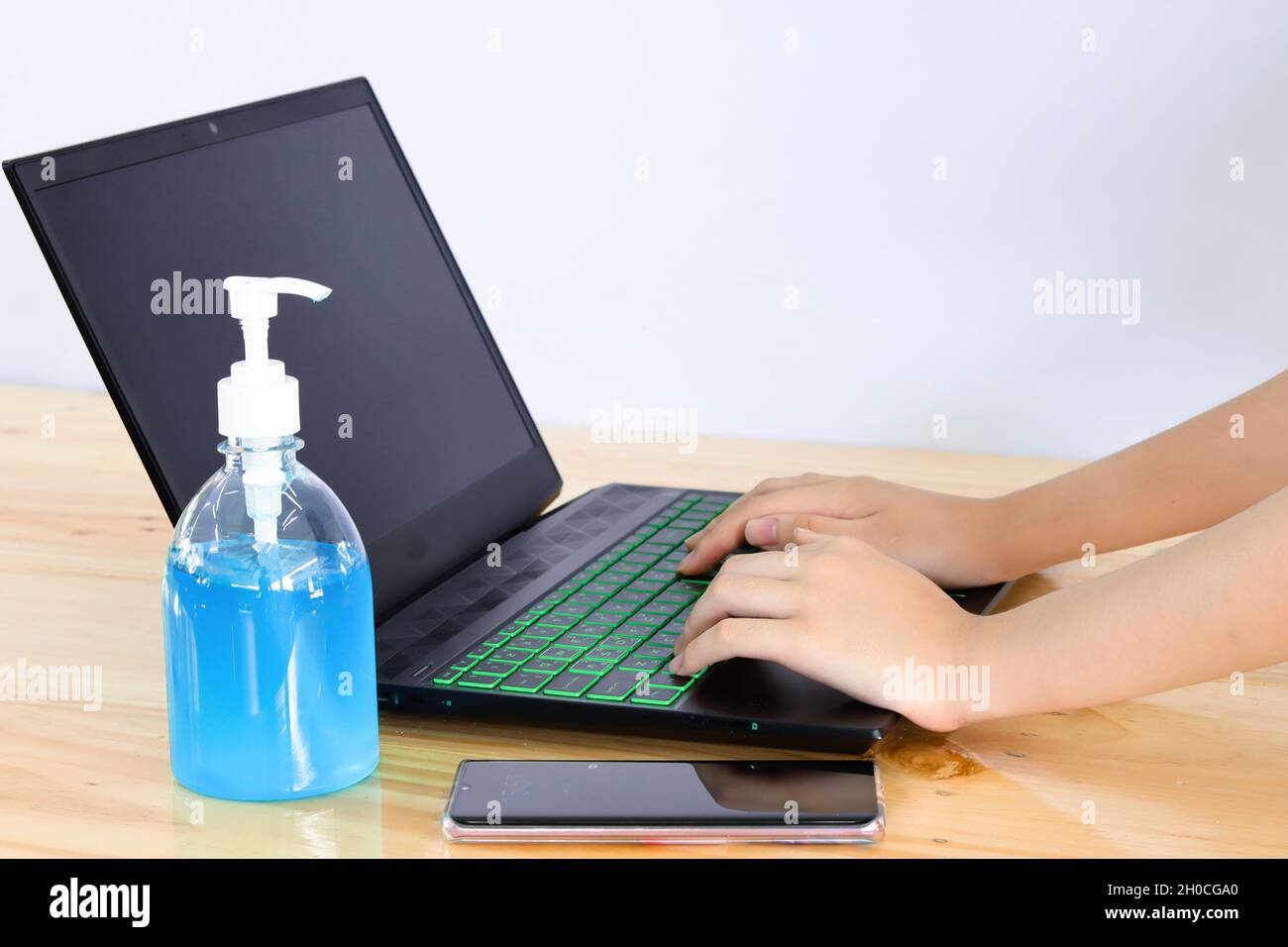 Hands, sanitizer gel and laptop computer on wood table, white