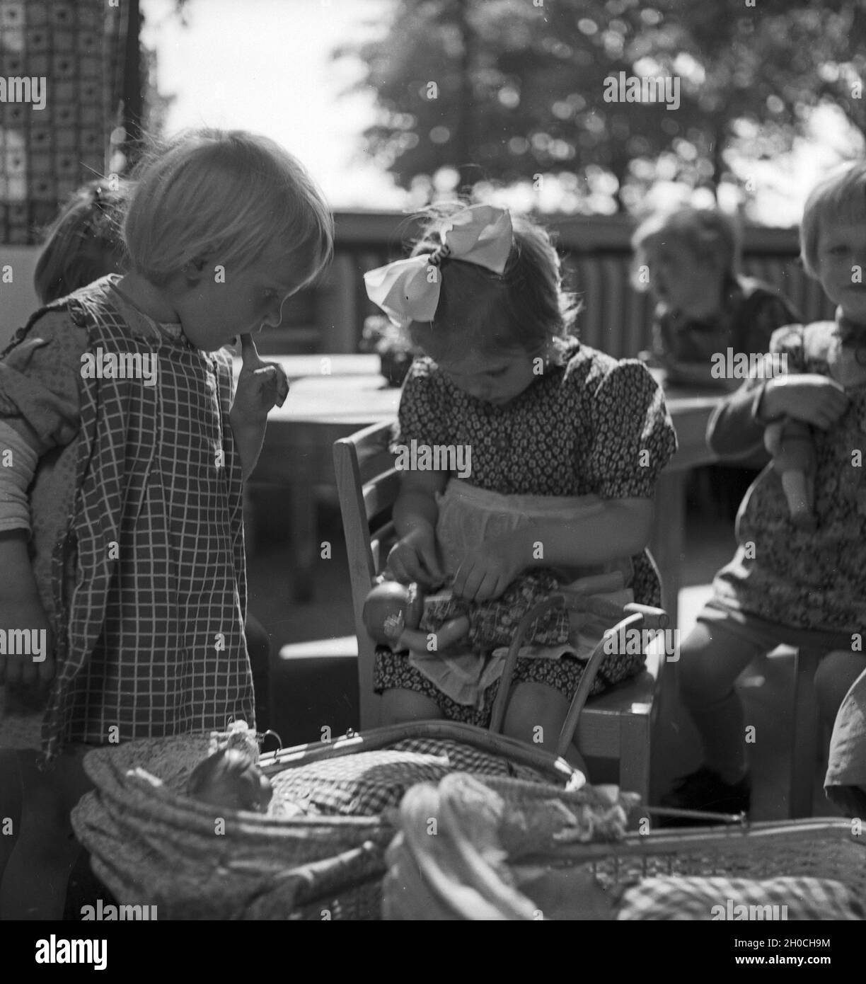 Eine Kindergärtnerin kümmert sich um die kleinen Kinder im Kindergarten, Deutschland 1930er Jahre. A nursery teacher with her children group at the Kindergarten, Germany 1930s. Stock Photo
