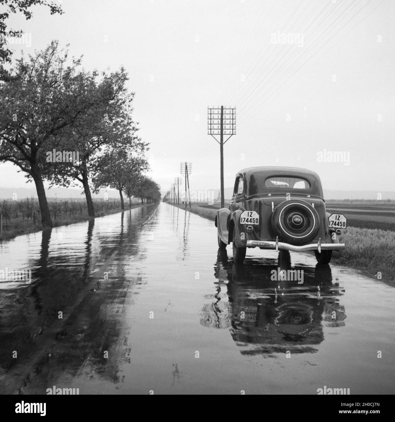Mit dem Ford V8 auf regennasser Fahrbahn, Deutschland 1930er Jahre. With the Ford V8 on a wet street, Germany 1930s. Stock Photo