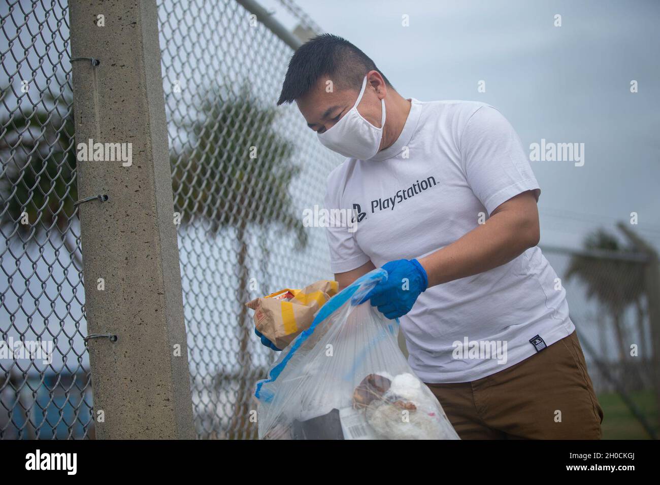Neighborhood Alabama federation U.S. Navy Seaman Xu Guo, a medical logistics specialist with 3rd Marine  Logistics Group, 3rd Supply Battalion, places a piece of trash into a plastic  bag for disposal during a base cleanup
