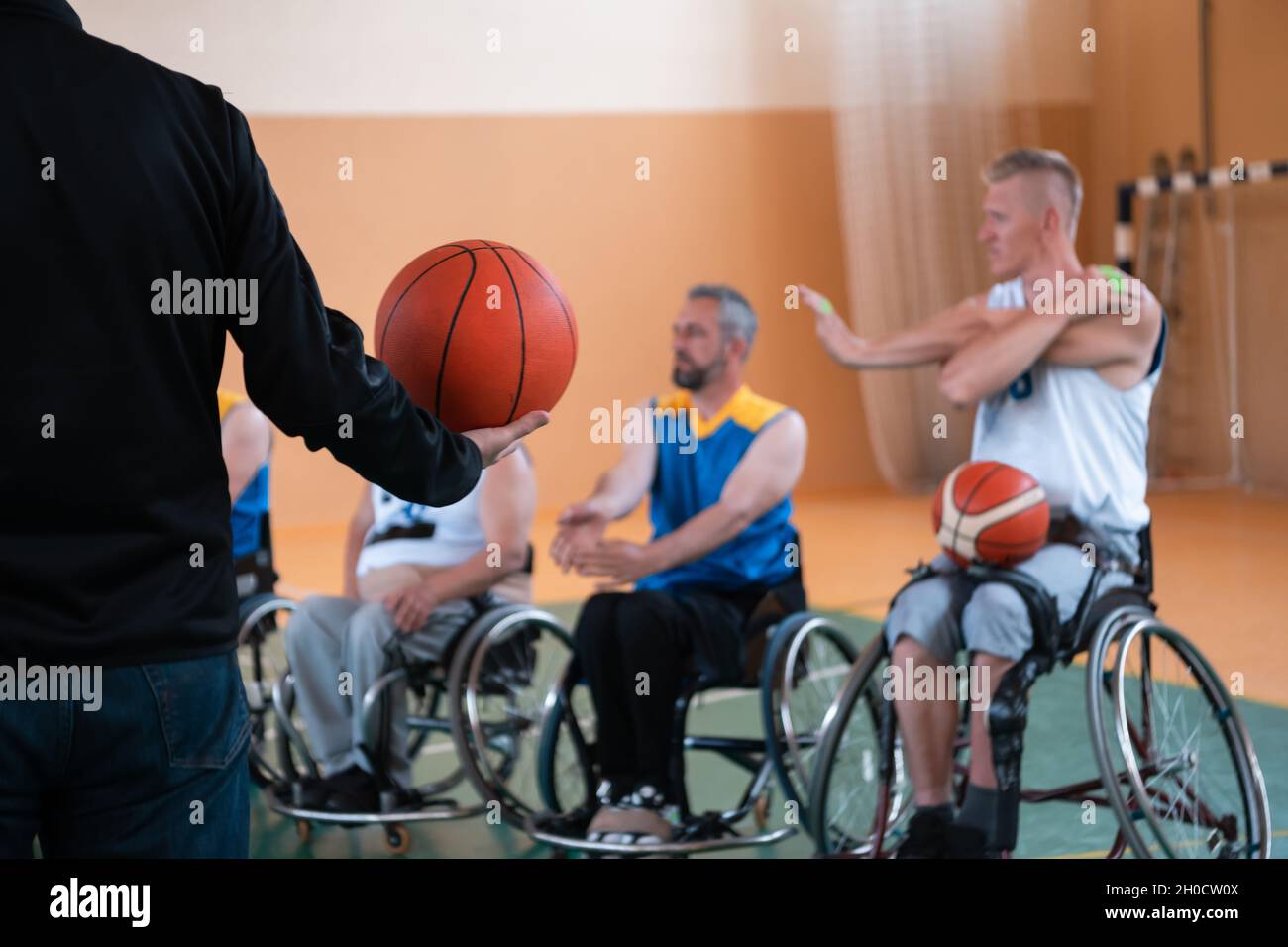 the selector of the basketball team with a disability stands in front of the players and shows