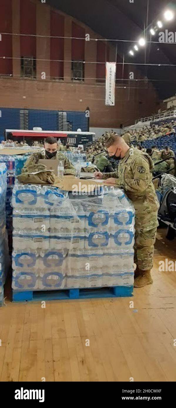 1st Lt. Robert Delotto, left, and Staff Sgt. Paul Salmi, both with the Massachusetts Army National Guard’s 110th Maintenance Company, use a pallet of water bottles as a workspace at the District of Columbia Armory in Washington, D.C., as they prepare their unit to assist  federal and district authorities, Tuesday, Feb. 2, 2021. The National Guard has been requested to continue supporting federal law enforcement agencies with security, communications, medical evacuation, logistics, and safety support to state, district and federal agencies through mid-March. Stock Photo