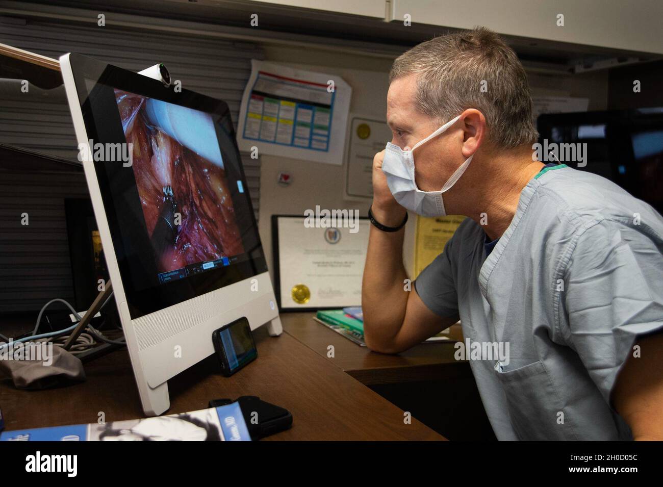 210127-N-LW757-1068  SAN DIEGO (Jan. 27, 2020) Capt. Gordon Wisbach, Naval Medical Center San Diego’s (NMCSD) Bio-skills Training and Simulation Center’s surgical director, mentors a surgical team from a remote office during a robotic-assisted laparoscopic inguinal hernia repair procedure Jan. 27. Robotic surgical systems, like those used at NMCSD, allow surgeons to perform minimally-invasive procedures, and this procedure was performed during a remote, tele-mentoring study. NMCSD’s mission is to prepare service members to deploy in support of operational forces, deliver high quality healthcar Stock Photo