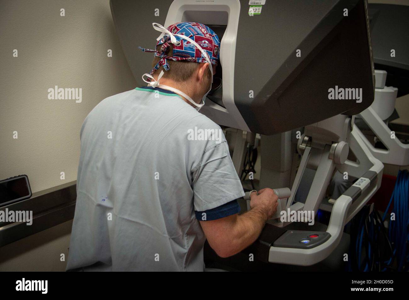 210127-N-LW757-1045  SAN DIEGO (Jan. 27, 2020) Jesse Bandle, a staff surgeon assigned to Naval Medical Center San Diego's (NMCSD) Main Operating Room, manipulates a robotic surgical system during a robotic-assisted laparoscopic inguinal hernia repair procedure in one of the hospital's operating rooms Jan. 27. Robotic surgical systems, like those used at NMCSD, allow surgeons to perform minimally-invasive procedures, and this procedure was performed during a remote, tele-mentoring study. NMCSD’s mission is to prepare service members to deploy in support of operational forces, deliver high quali Stock Photo