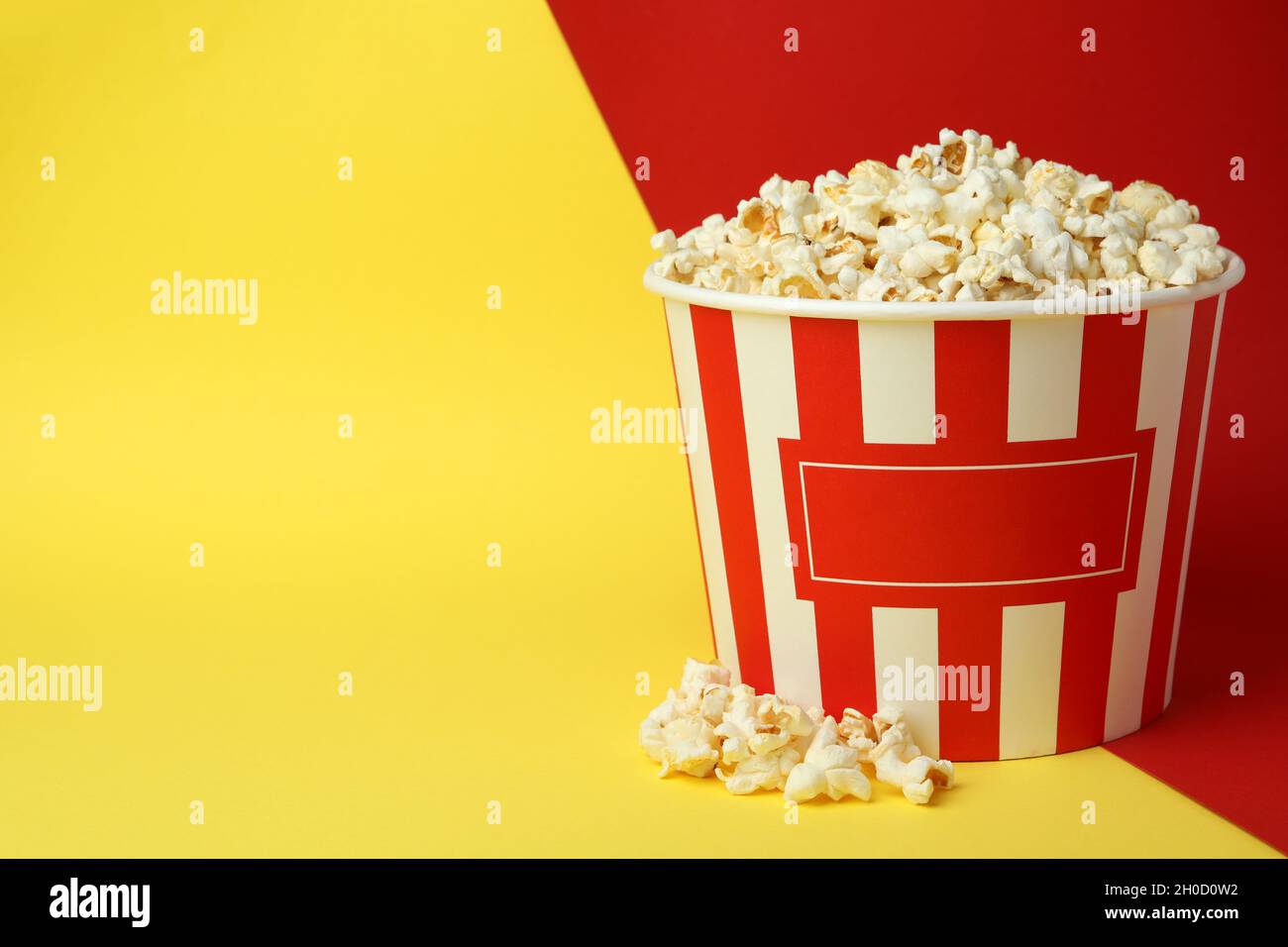 Striped paper cup with popcorn on two tone background. Stock Photo
