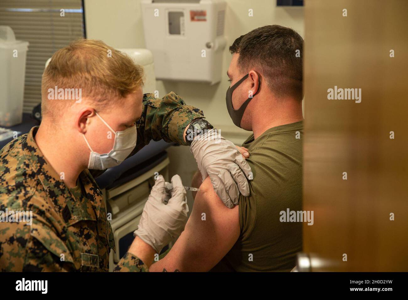 U.S. Marine Sgt. Tobey Clements, right, a helicopter airframe mechanic with Marine Light Attack Helicopter Squadron 369, Marine Aircraft Group 39, 3rd Marine Aircraft Wing, receives the COVID-19 vaccine at the 22 Area Marine Centered Medical Home on Marine Corps Base Camp Pendleton, California,  Jan. 29, 2021. COVID-19 vaccines are being administered in a phased approach, prioritizing healthcare workers and first responders, as well as mission critical and deploying personnel. Vaccination distribution prioritization within DOD, and the Marine Corps, will be consistent with data-driven CDC guid Stock Photo