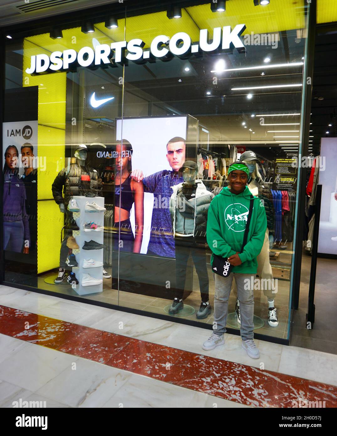 Young boy posing for photograph in front of JD Sports in Brent Cross