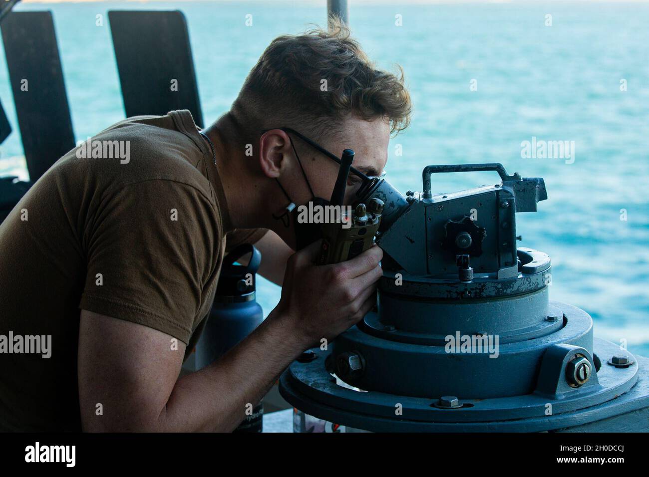 210131-A-BD272-0106 ARABIAN GULF (Jan. 31, 2021) - Information Systems Technician 2nd  Class Ryan Way, assigned to patrol coastal ship USS Chinook (PC 9), takes bearings using a  telescopic alidade in the Arabian Gulf, Jan. 31. Chinook is deployed to the U.S. 5th Fleet area of  operations in support of naval operations to ensure maritime stability and security in the Central  Region, connecting the Mediterranean and Pacific through the western Indian Ocean and three  strategic choke points. Stock Photo