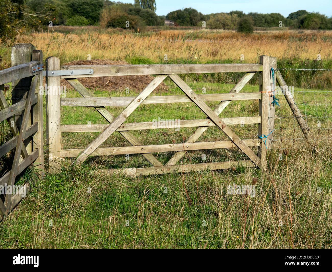Wooden farm gate in a grassy field Stock Photo