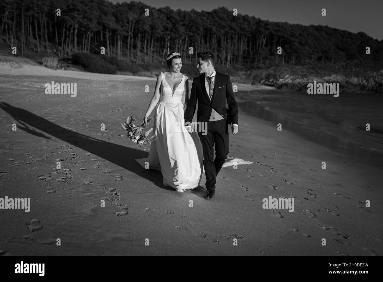 Just married couple walking on a beach on black and white Stock Photo ...