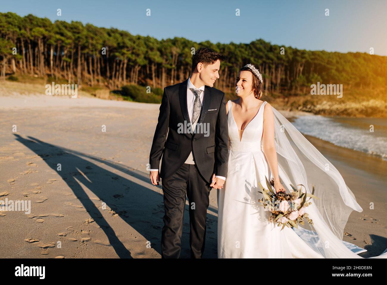 Just married couple walking on a beach at sunset Stock Photo - Alamy