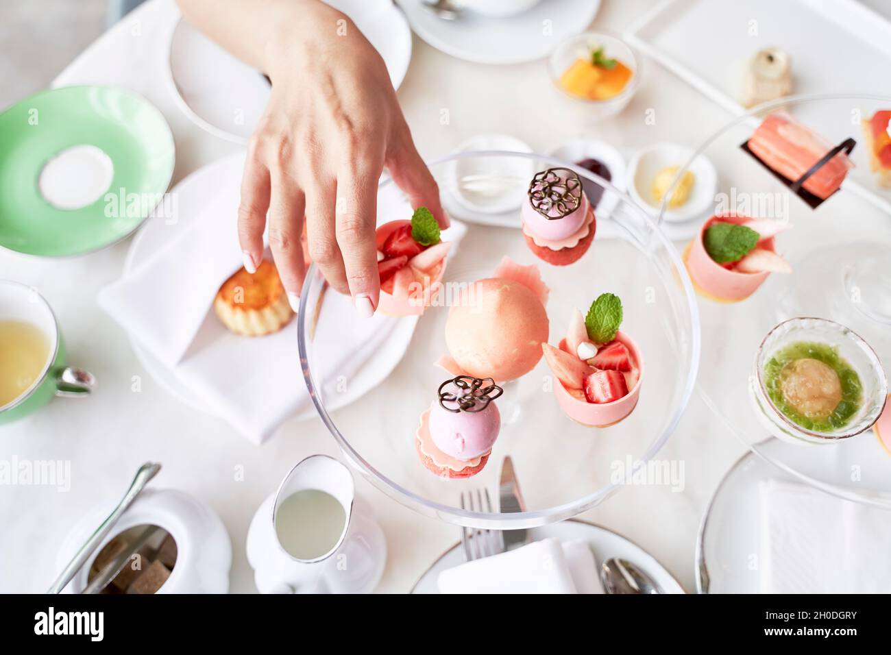 high angle view of hand of asian woman picking a dessert from glass plate on table Stock Photo