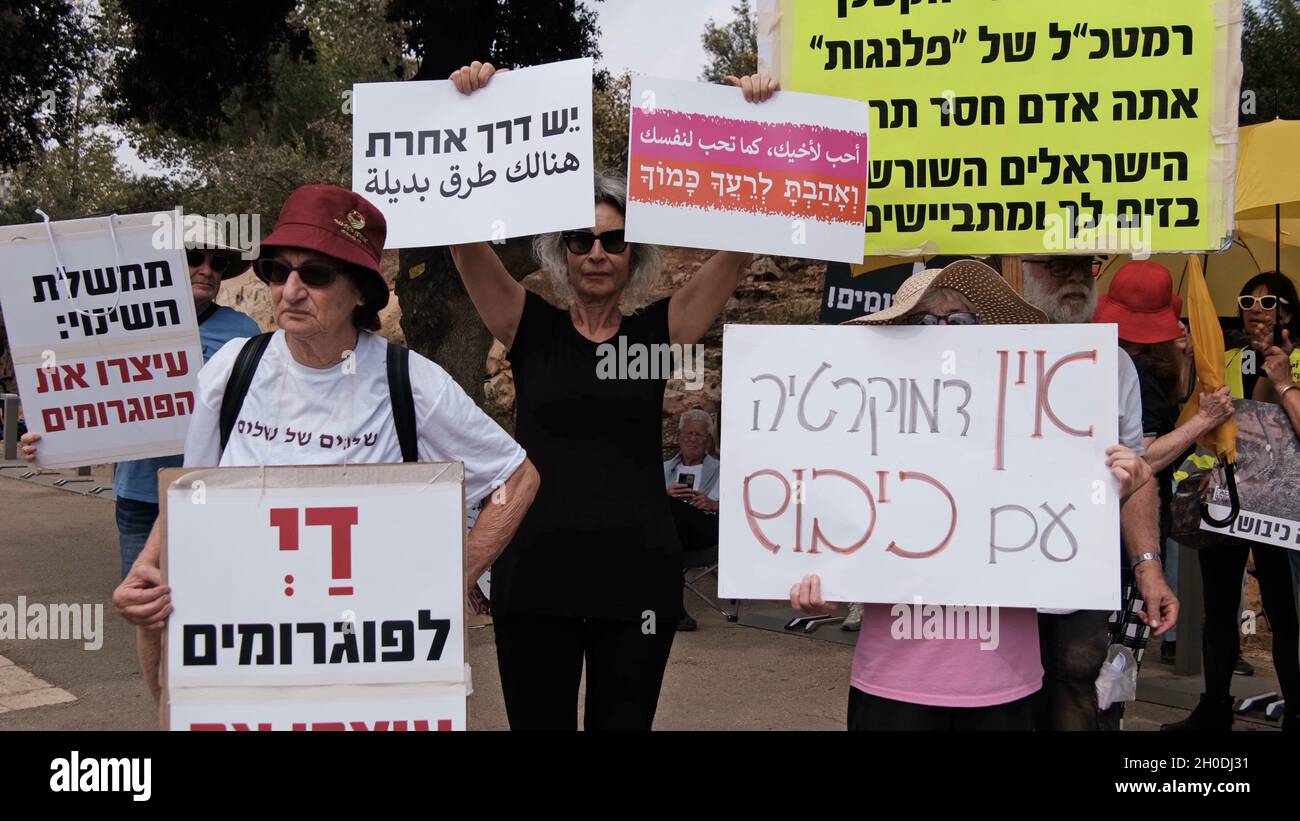 JERUSALEM, ISRAEL - OCTOBER 12: Israeli left-wing activists and supporters of the Peace Now movement hold placards as they take part in a demonstration against Israeli settler violence on Palestinians in the West Bank in front of the Israeli Parliament, Knesset on October 12, 2021 in Jerusalem, Israel. The number of incidents involving physical attacks by Jewish Settlers on Palestinians in the West Bank has risen dramatically In the first half of 2021, 416 anti-Palestinian incidents were reported more than double the figure for the first half of 2020. Stock Photo