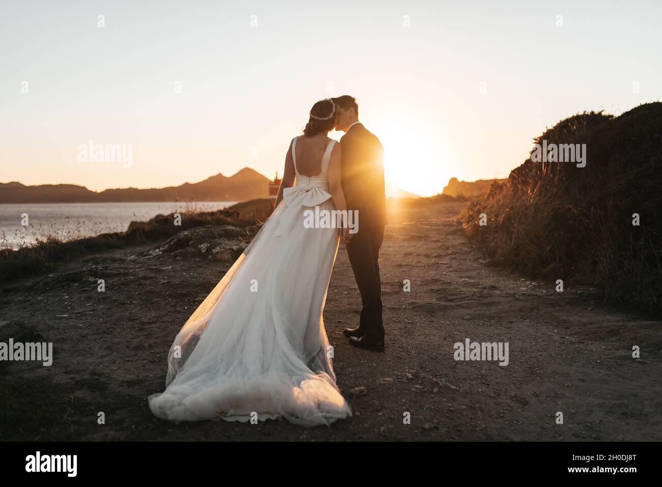 Just married couple kissing near the ocean at sunset Stock Photo - Alamy