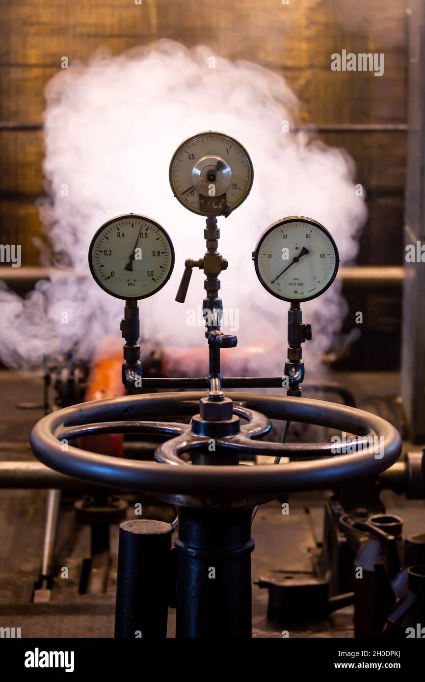 Old analog pressure gauges on an industrial steam plant. Photo taken in low light conditions, natural light Stock Photo