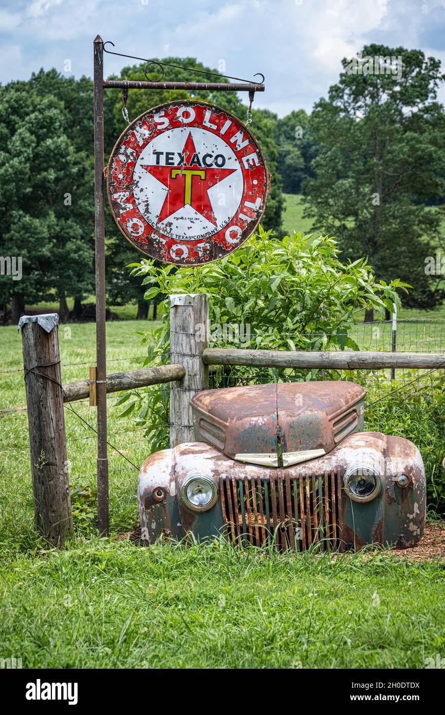 Vintage Texaco Gasoline & Motor Oil sign with the weathered front end of a classic Ford vehicle at Crazy Mule Art & Antiques in Lula, Georgia. (USA) Stock Photo