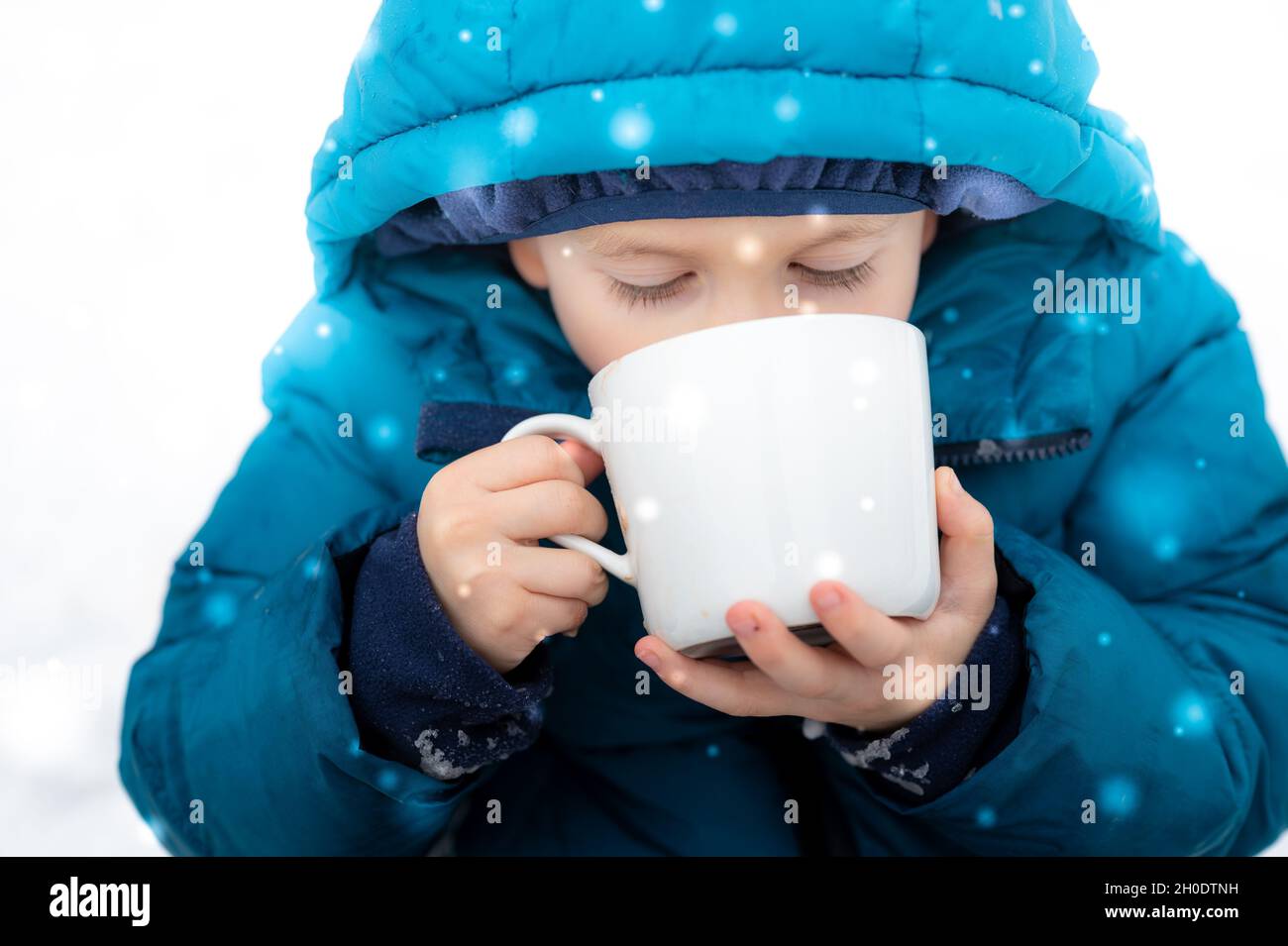 Little boy drinking hot cocoa in on a snowy day Stock Photo