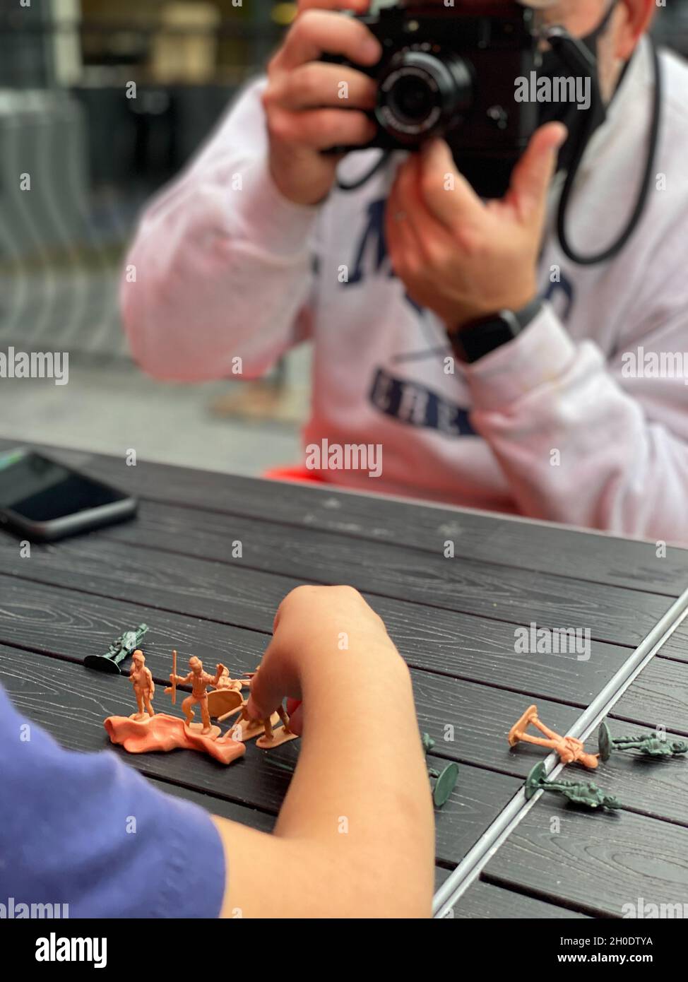 Father photographing son playing with toy soldiers Stock Photo