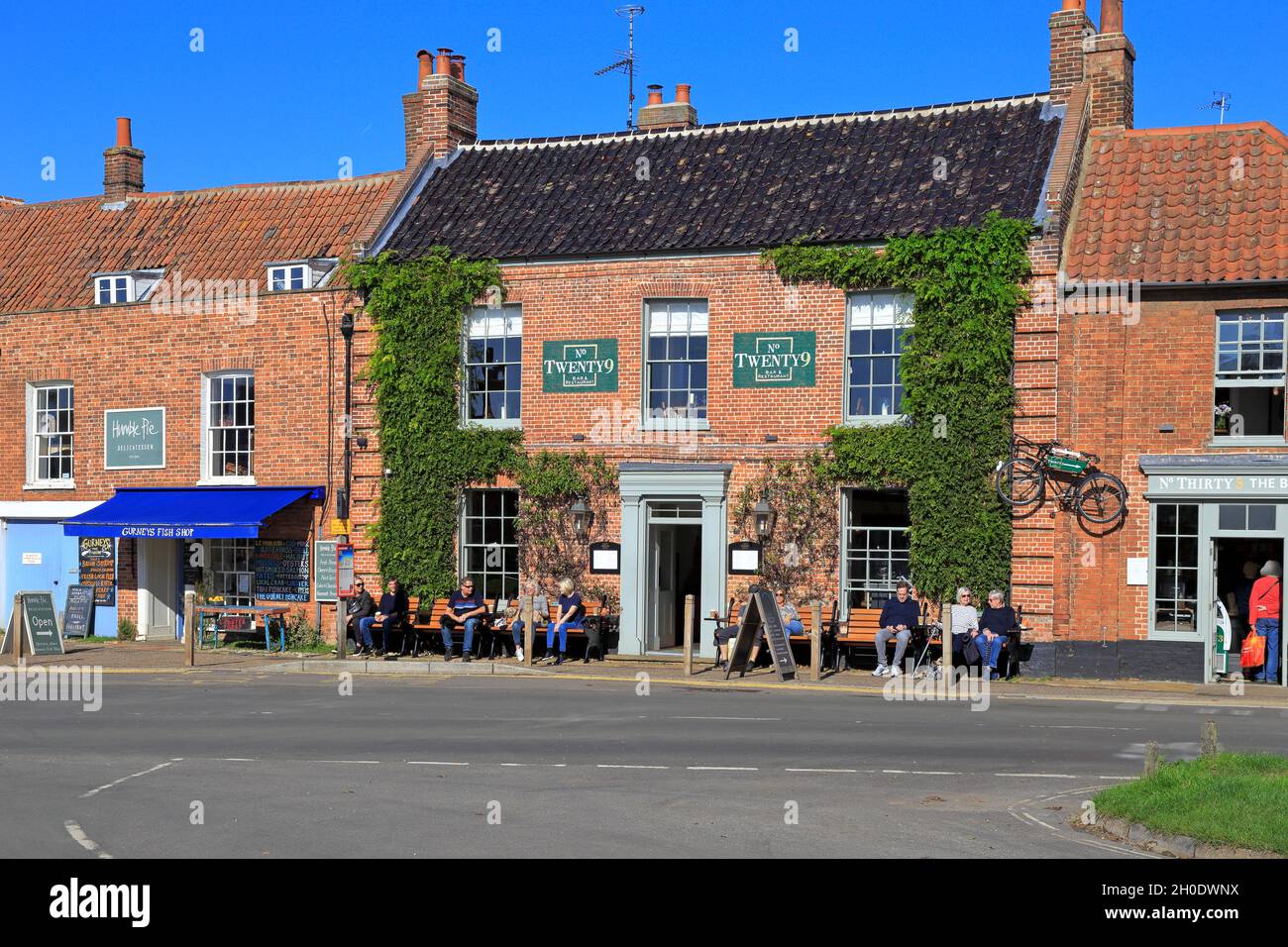 People sat outside No Twenty9 bar and restaurant, Market Place, Burnham Market, Norfolk, England, UK. Stock Photo