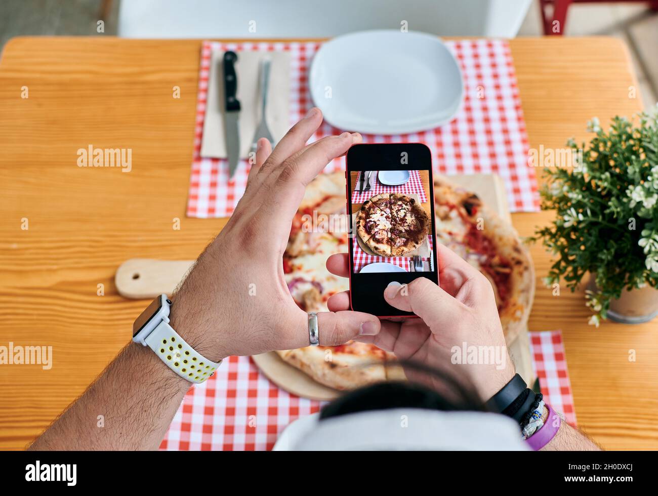 Close-up of a man taking pictures of a pizza with his phone Stock Photo