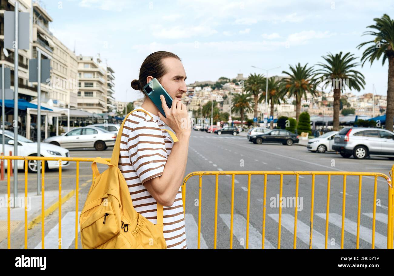 Young man with backpack walking on the street of city Kavala, Greece Stock Photo