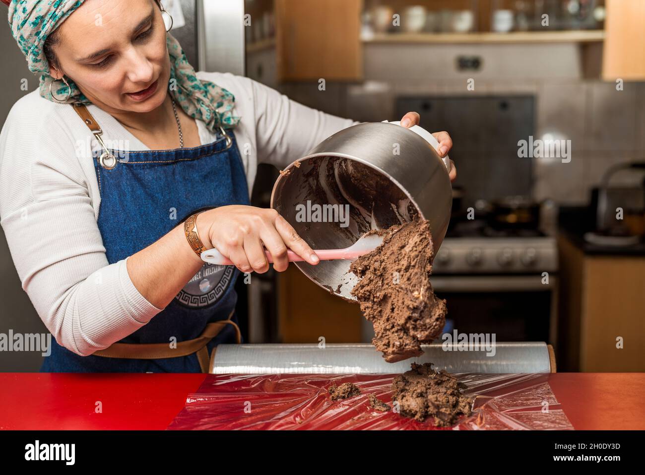 Female cook removing the mixture of ingredients from a pot on a kitchen transparent film for the preparation of the homemade Argentine alfajores recip Stock Photo