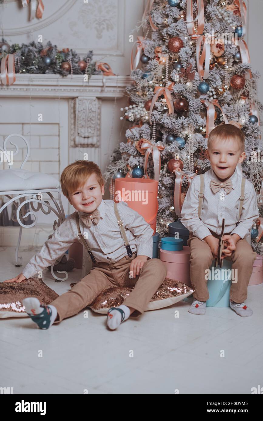 Cheerful cute children boys opening gifts under christmas tree Stock Photo