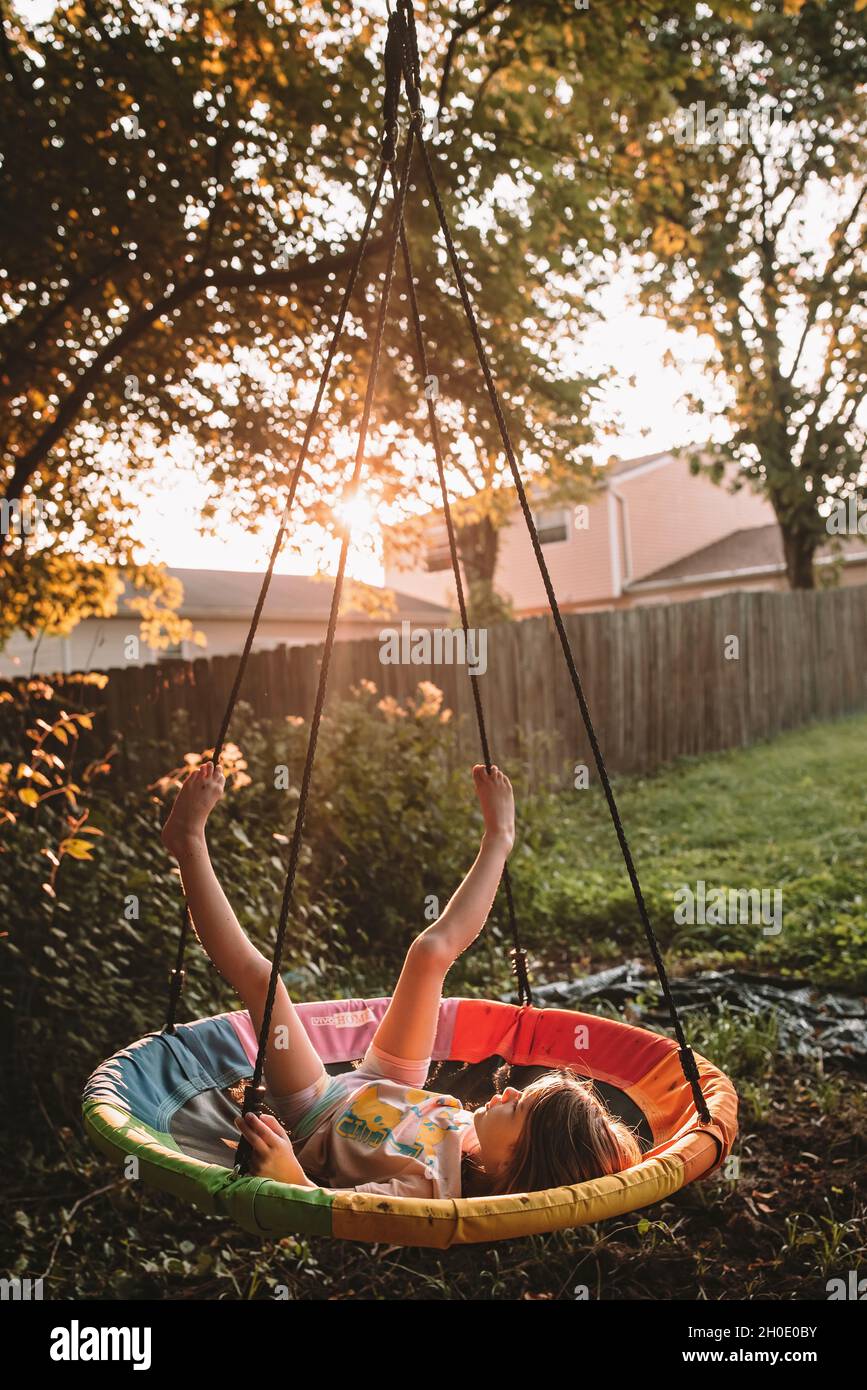 Swinging on her tree swing at sunset Stock Photo