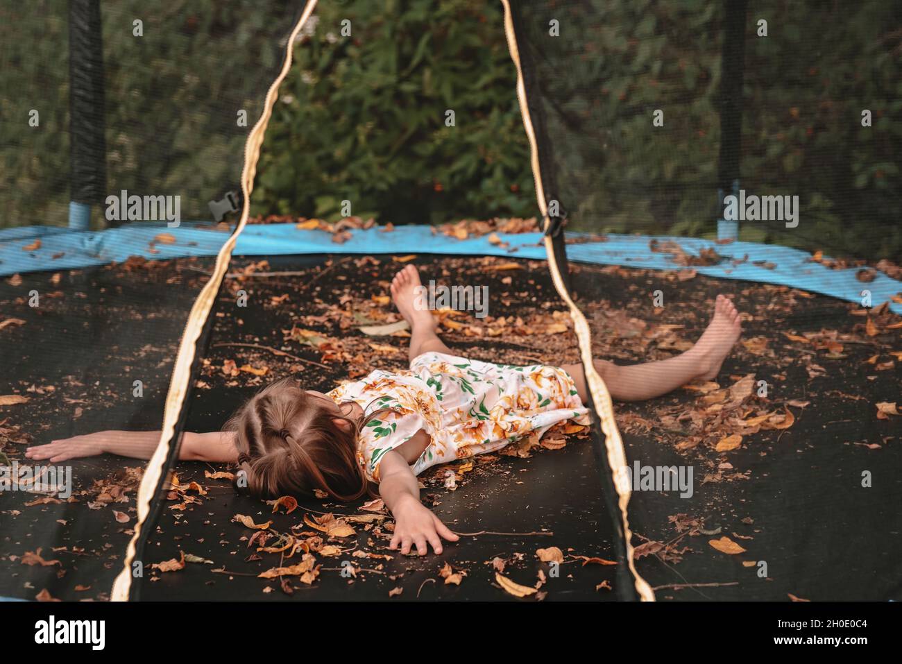 Playing in the autumn leaves on her trampoline Stock Photo