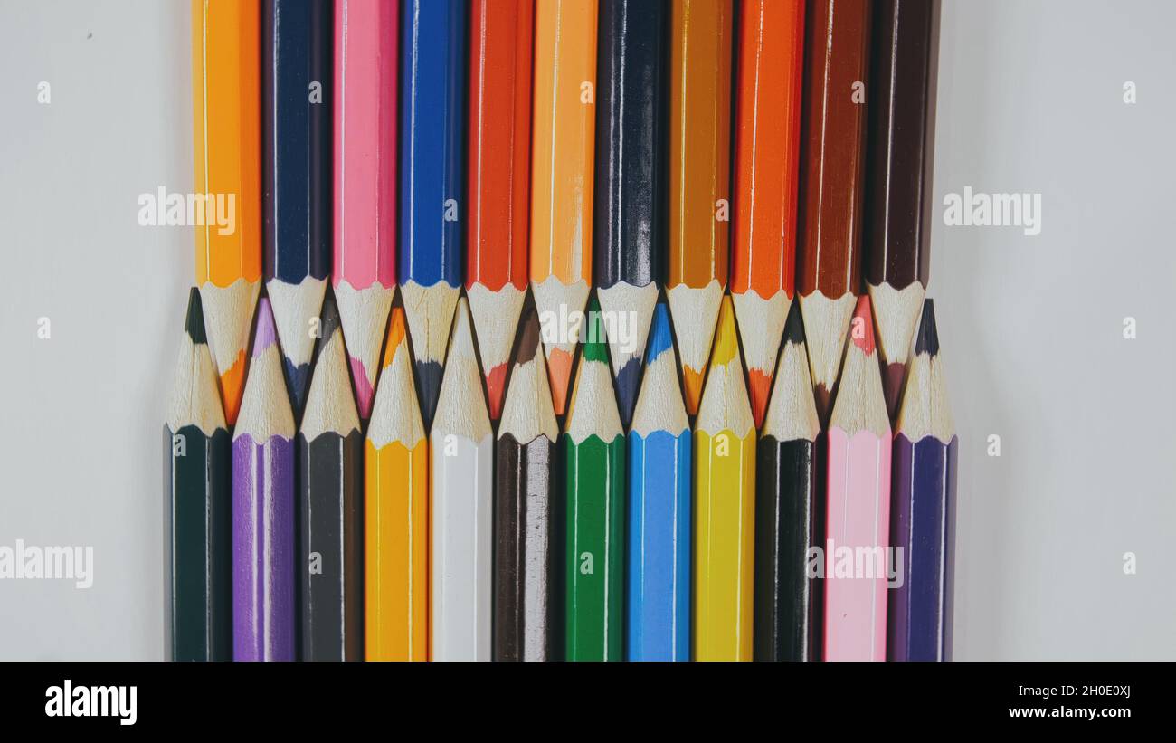 Many colored pencils are arranged around the edges of the image as a frame. In the center is an empty background with space for text. Stock Photo