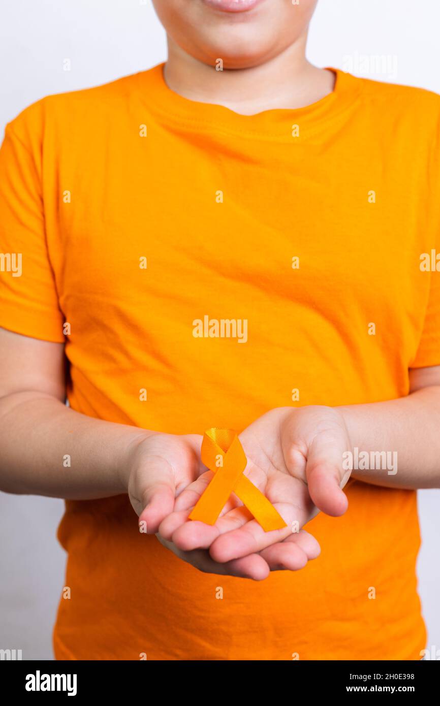 Boy holding kidney cancer awareness orange ribbon in his hands Stock