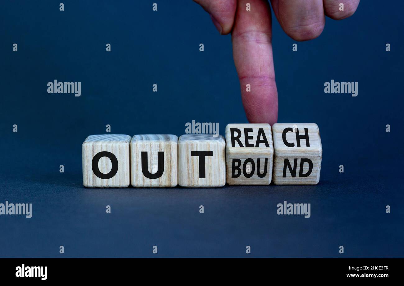Outreach or outbound symbol. Businessman turns wooden cubes and changes the word 'outbound' to 'outreach'. Beautiful grey table grey background. Busin Stock Photo