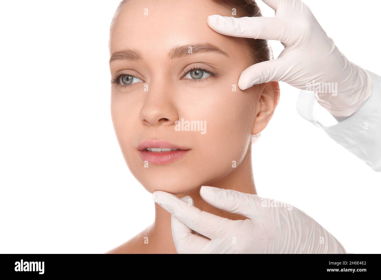 Doctor examining young woman face before cosmetic surgery on white