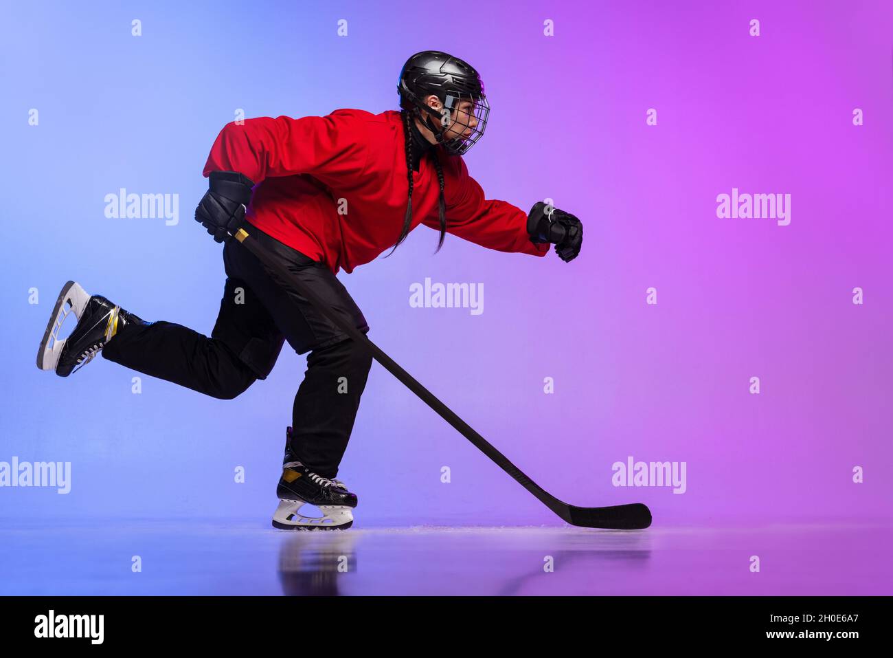 Fulllength portrait of professional female hockey player training, dribbling puck isolated over
