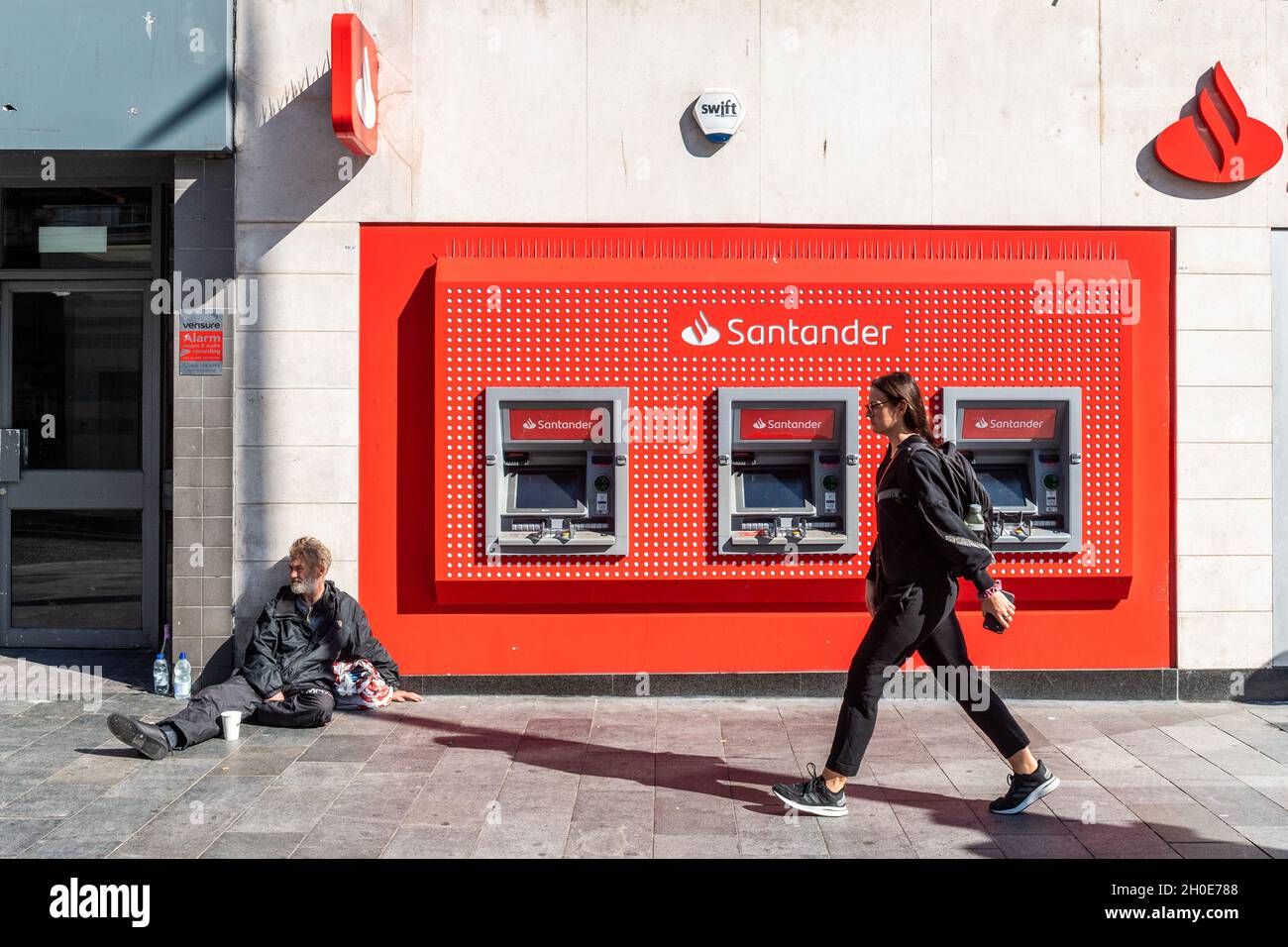 Homeless man sitting next to Santander Bank ATM's, Liverpool, Merseyside, UK. Stock Photo