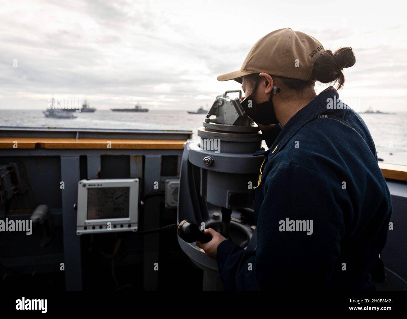 Conning Officer Ensign Marion Bautista, from Chicago, looks through a telescopic alidade on the bridge wing aboard the Arleigh Burke-class guided-missile destroyer USS John S. McCain (DDG 56) as the ship sails in formation with ships from the Nimitz and Theodore Roosevelt Carrier Strike Group during dual carrier operations. McCain is assigned to Destroyer Squadron (DESRON) 15, the Navy’s largest forward-deployed DESRON and the U.S. 7th Fleet’s principal surface force. Stock Photo