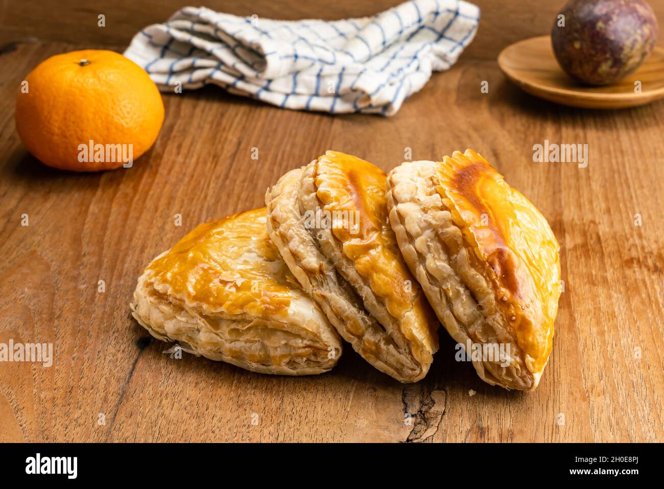 Delicious homemade tuna pie on wooden table with passion fruit in wooden plate, ripe orange and cloth. Stock Photo