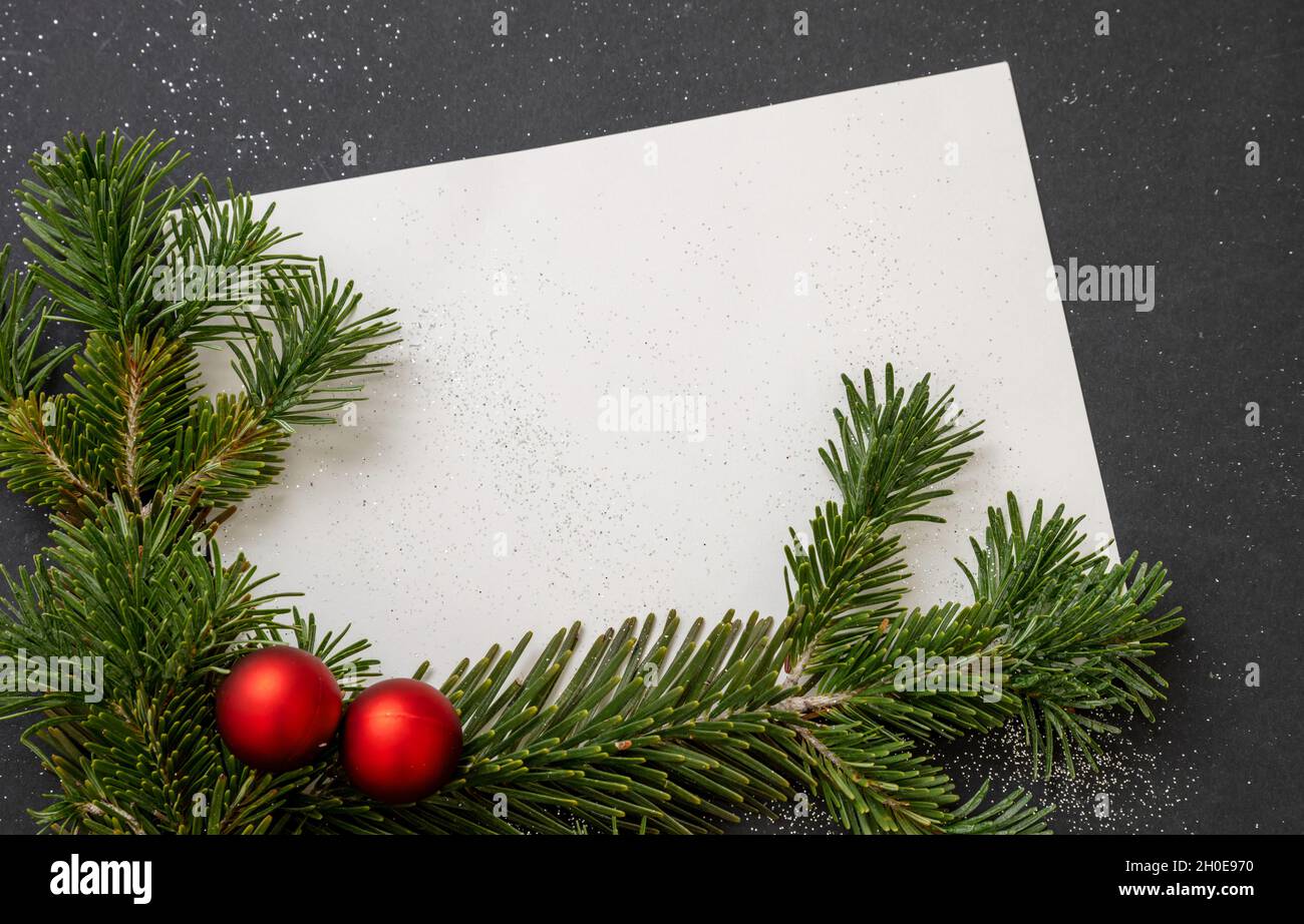 Christmas greeting card template. Empty space for New Year wishes. White  blank paper message note, fresh fir twig and red Xmas baubles on black  backgr Stock Photo - Alamy