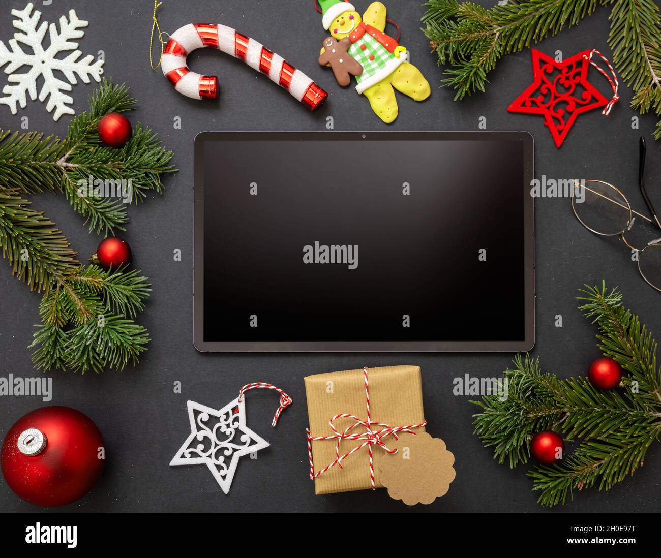 Christmas decoration and digital tablet on black background. Blank screen electronic device, copy space, greeting card template, top view Stock Photo