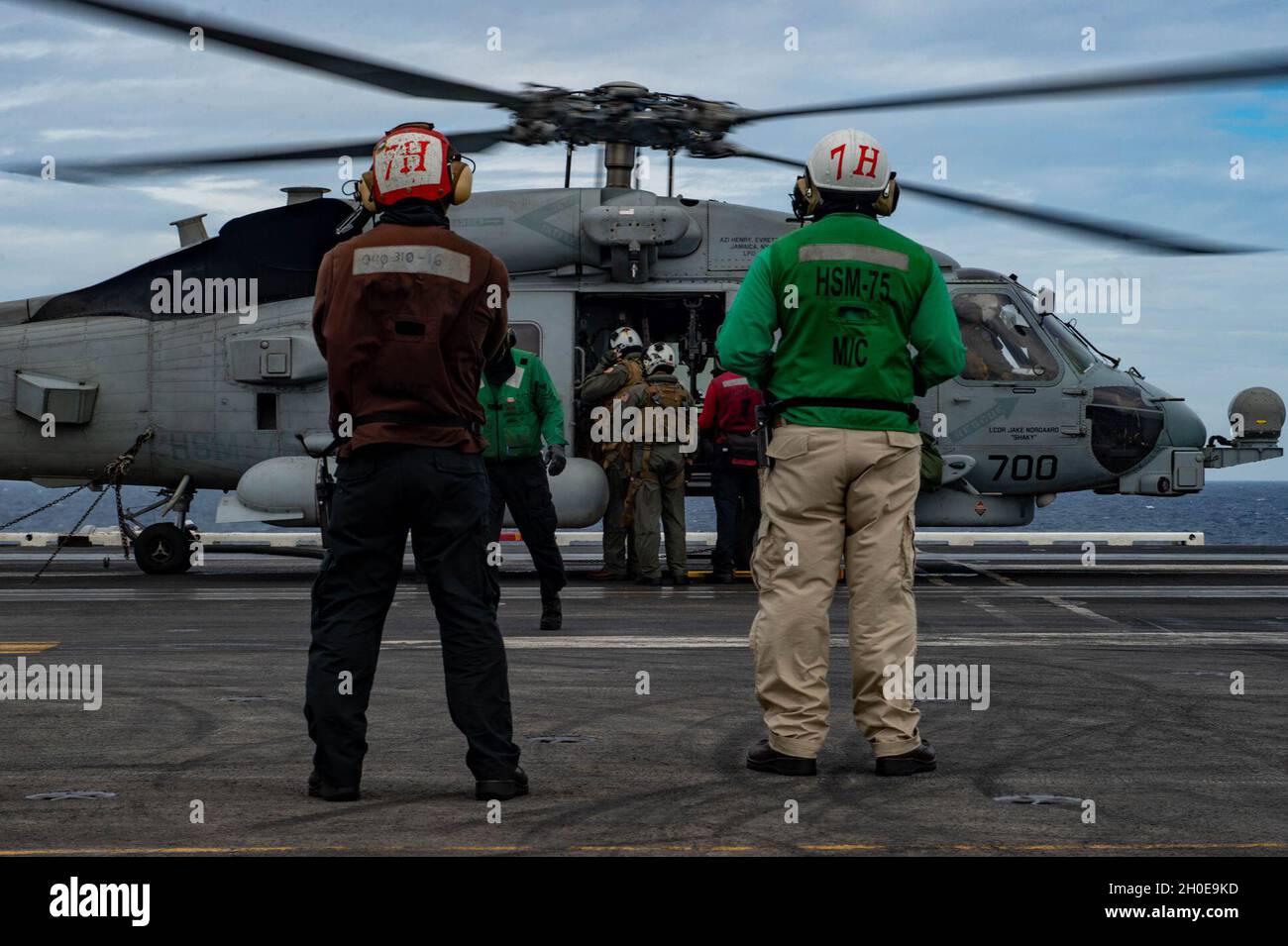 SOUTH CHINA SEA (Feb. 9, 2021) – U.S. Navy Aviation Machinist’s Mate 2nd Class Aaron Decano, from Baguio City, Philippines, left, and Chief Aviation Machinist’s Mate Arturo Perez, from El Paso, Texas, observe a crew swap of an MH-60R Sea Hawk, assigned to the “Wolf Pack” of Helicopter Maritime Strike Squadron (HSM) 75, during flight operations on the flight deck of the aircraft carrier USS Theodore Roosevelt (CVN 71) Feb. 9, 2021. The Theodore Roosevelt and Nimitz Carrier Strike Groups are conducting dual-carrier operations during their deployments to the 7th Fleet area of operations. As the U Stock Photo