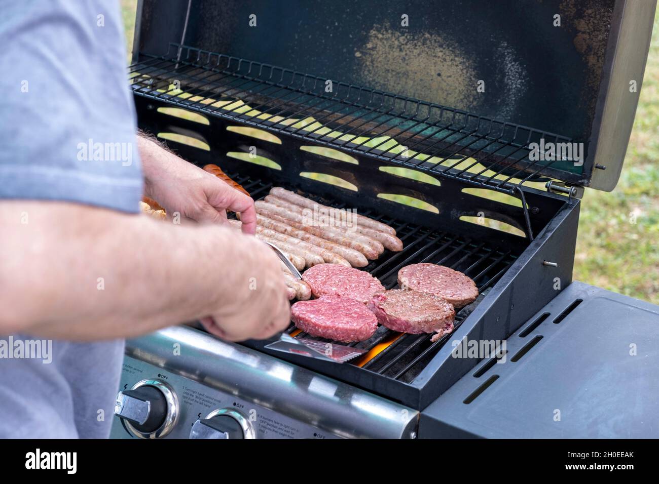 Meat cooked on a gas BBQ, sausages, chipolatas, kebabs and minced beef. Stock Photo