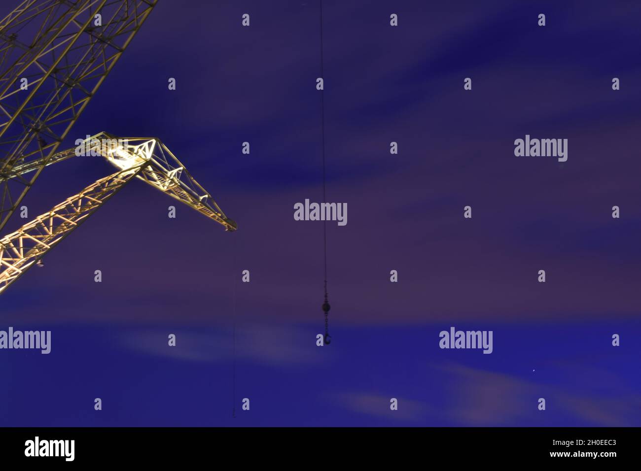 Low angle view of illuminated yellow industrial metal crane structure ...