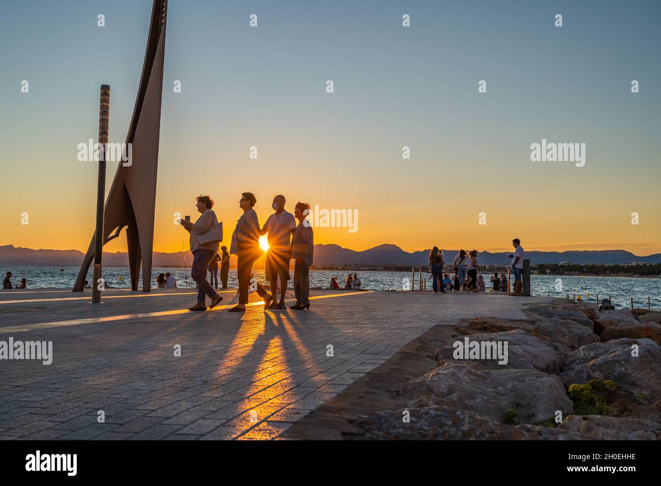 SALOU, SPAIN - SEPTEMBER 19.2021: Silhouette of people watching sunset at the coastline Costa Dorada, promenade Salou, Spain. Stock Photo