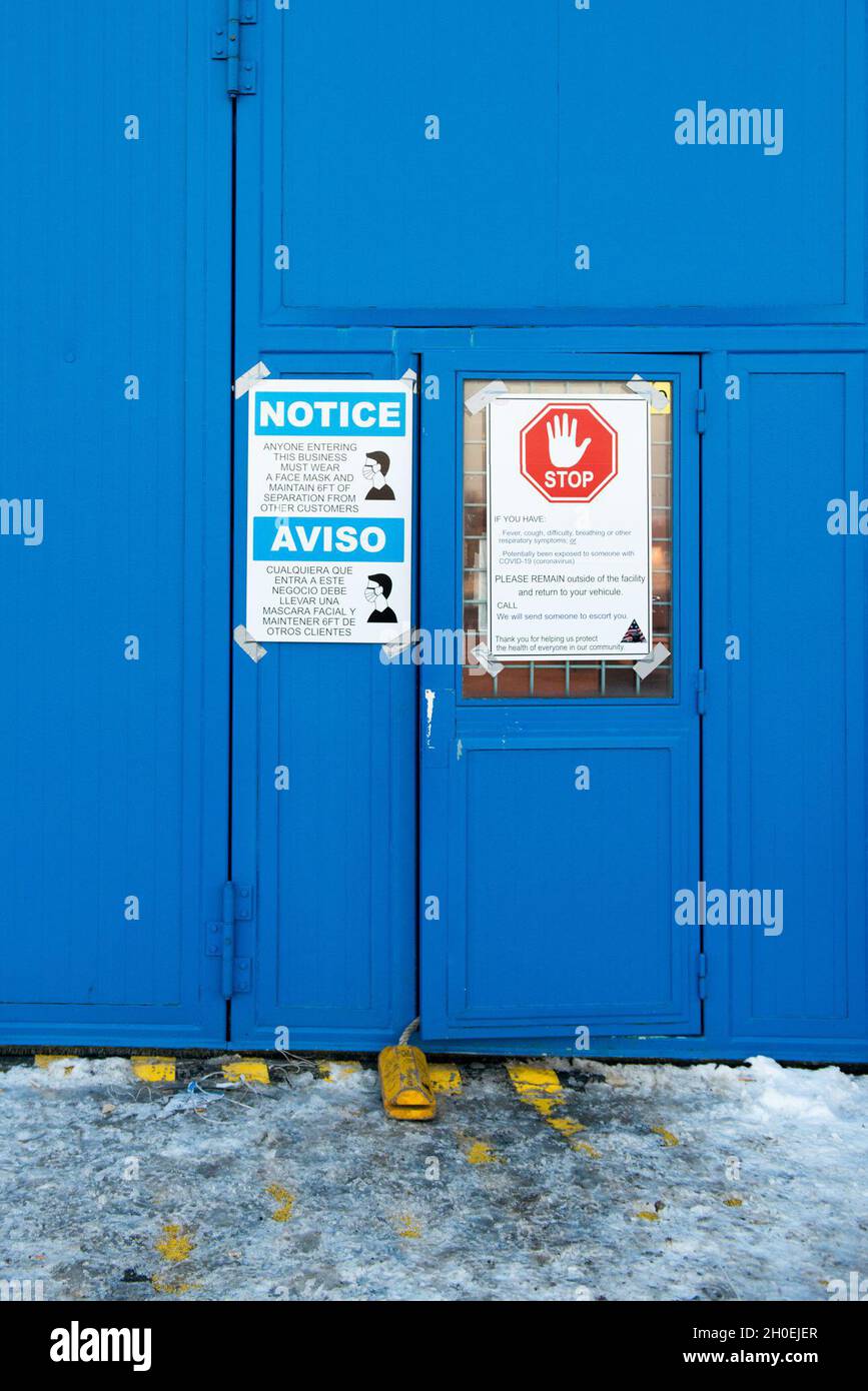 Covid-19 signage describe safety measures on the door of a hangar that ...